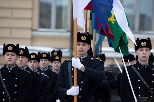 Sotilaita muodossa mustissa puvuissa. Osa pitelee lippua.